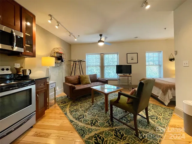 a living room with furniture a flat screen tv and kitchen view