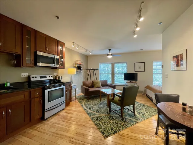 a living room with furniture wooden floor and a kitchen view