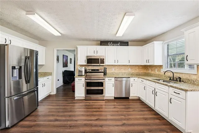 a kitchen with granite countertop a refrigerator oven a sink dishwasher and wooden floor