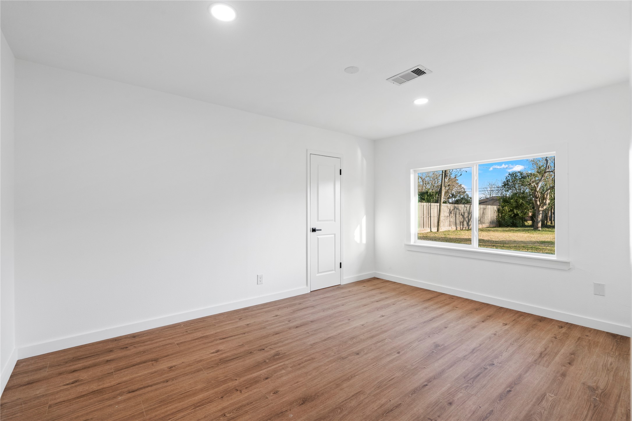 5023 Redstart Street Houston, TX 77035 - Photo 31 of 34 Oversized windows frame views of the expansive greenery outside, filling this spacious bedroom with a bright and airy ambiance.