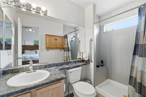 a bathroom with a granite countertop sink toilet a mirror a vanity and shower