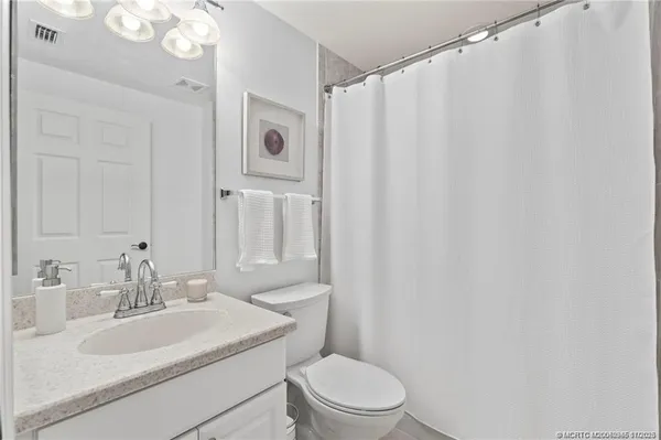 a bathroom with a sink vanity mirror and toilet