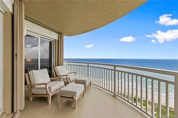 a balcony with couple of chairs and wooden floor