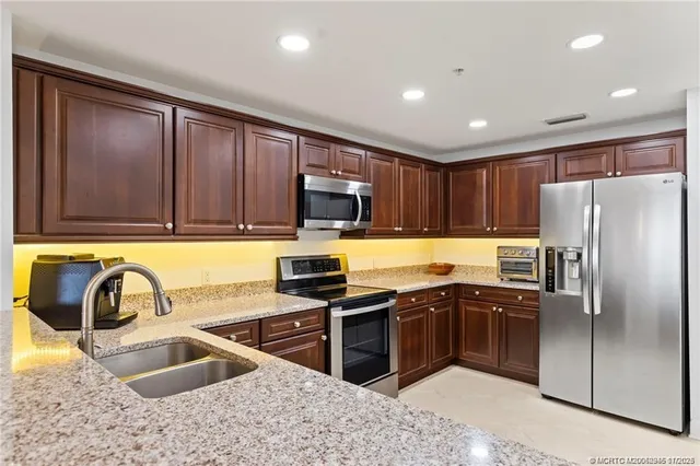 a kitchen with stainless steel appliances granite countertop a sink stove and refrigerator