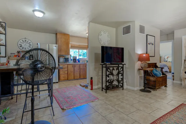 a living room with furniture a flat screen tv and a refrigerator