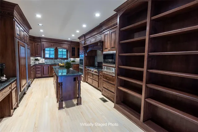 a kitchen with stainless steel appliances kitchen island granite countertop a stove refrigerator and a wooden cabinets