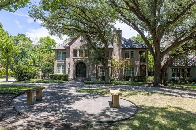a front view of a house with garden and trees