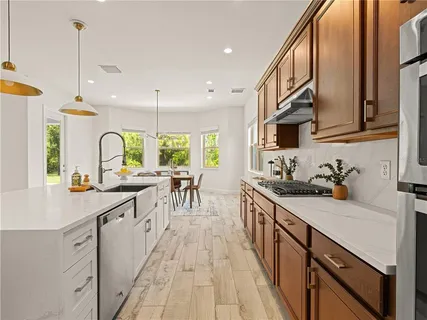 a kitchen with stainless steel appliances a sink a stove and a wooden floors