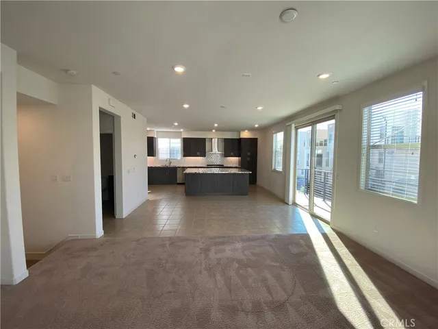 a living room with stainless steel appliances kitchen island granite countertop a sink and cabinets