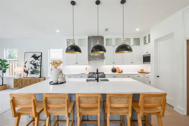 a kitchen with stainless steel appliances a sink stove and white cabinets with wooden floor