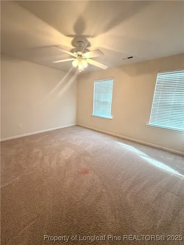 an empty room with windows and fan
