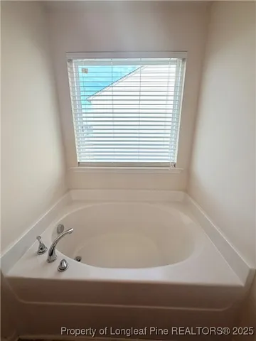 a white bath tub sitting in a bathroom next to a window