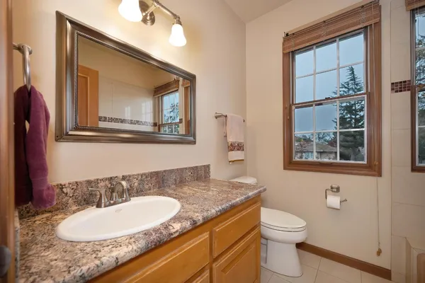 a bathroom with a granite countertop toilet a sink and a mirror
