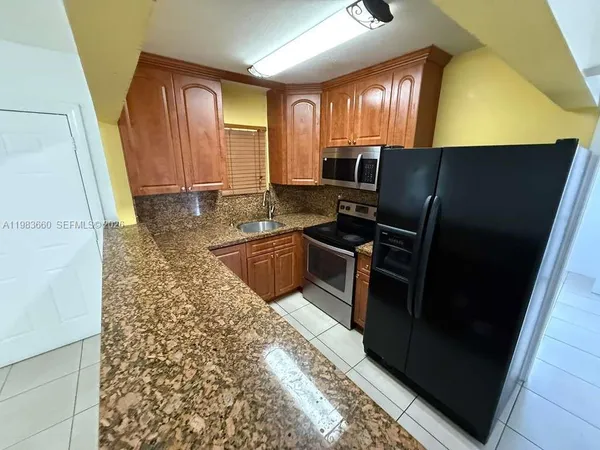 a kitchen with granite countertop a refrigerator stove and sink