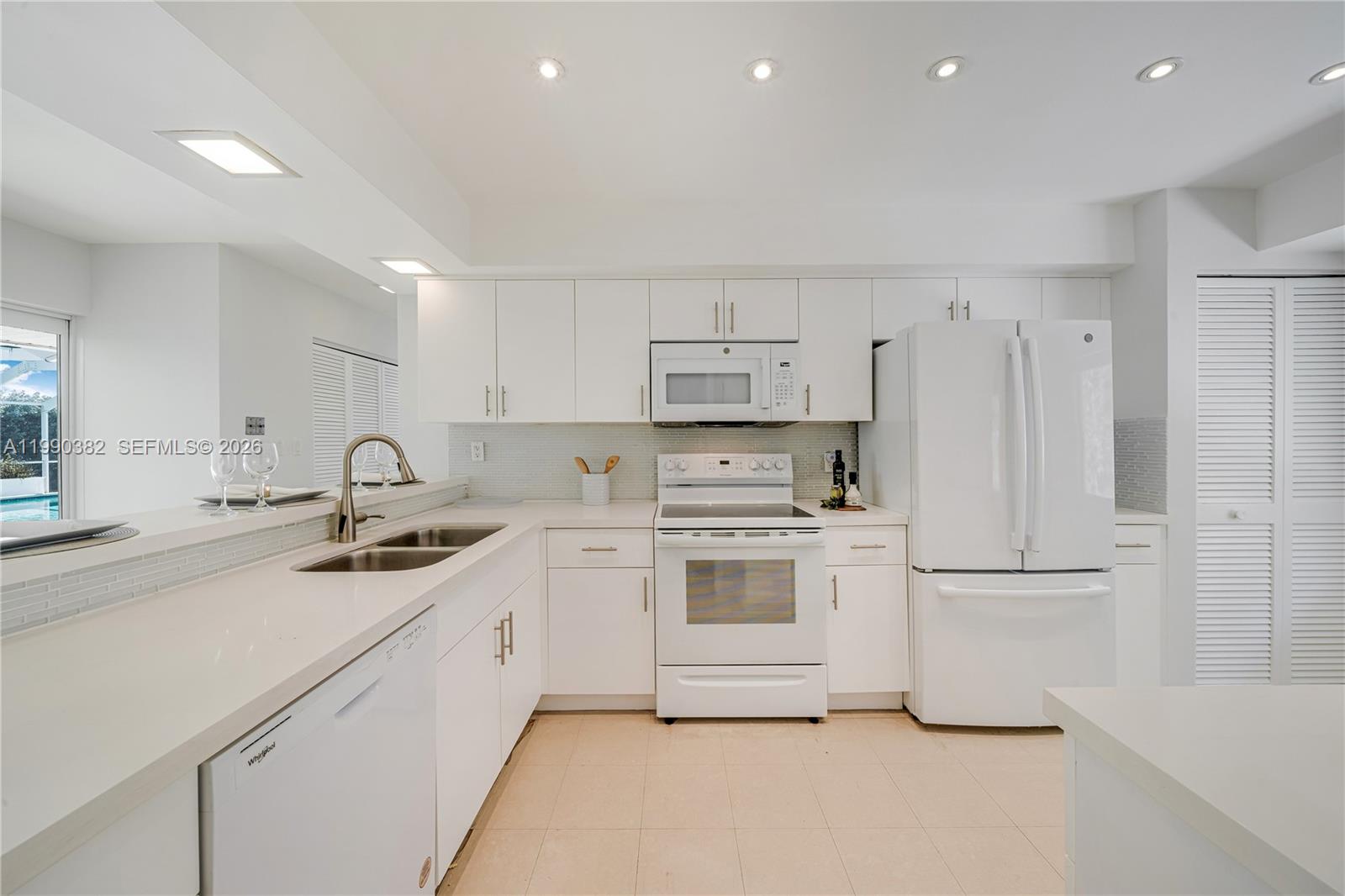 640 South Mashta Drive Key Biscayne, FL 33149 - Photo 18 of 38 a kitchen with white cabinets stainless steel appliances and sink
