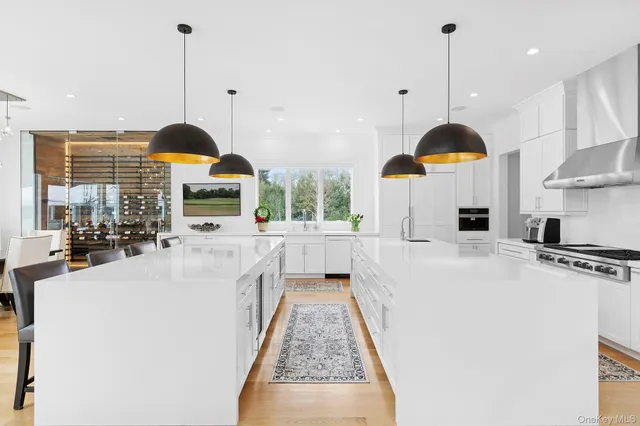 a open kitchen with stainless steel appliances granite countertop a stove a sink a oven and a large window with wooden floor