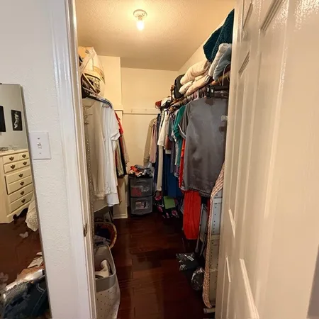 a view of walk in closet with clothes and shoes