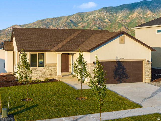 Single-story residence featuring a brown garage door, stone and stucco exterior, and a manicured lawn