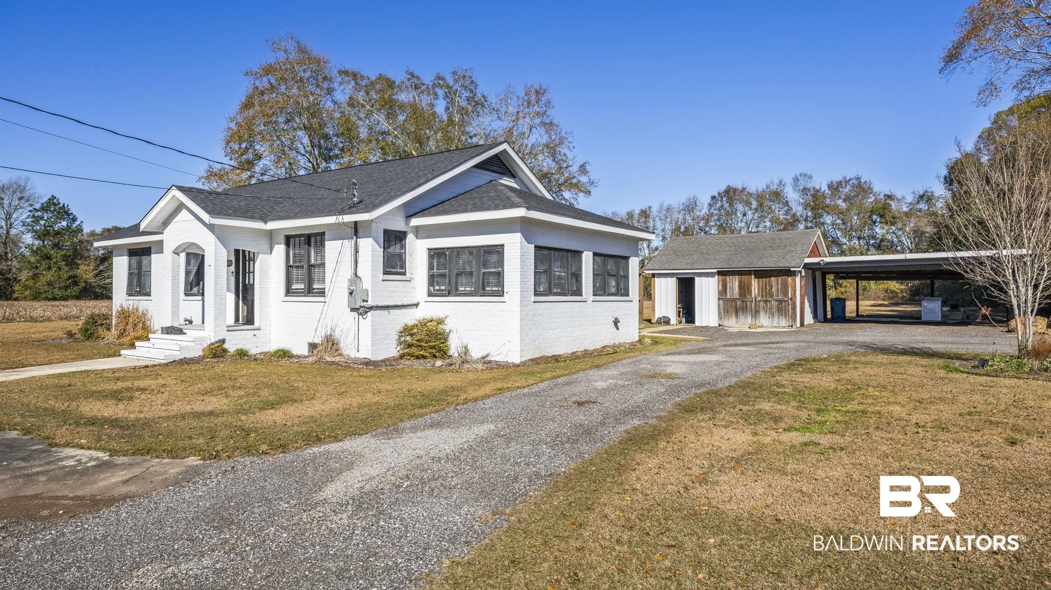 24701 Highway 98 Elberta, AL 36530 - Photo 2 of 32 View of front of home featuring brick siding, a front lawn, an outbuilding, gravel driveway, and roof with shingles