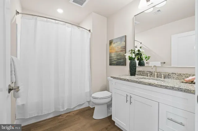 a bathroom with a granite countertop sink toilet and mirror