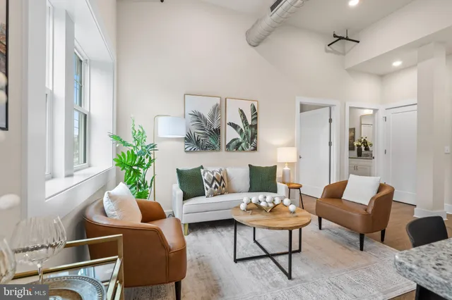 a living room with furniture potted plant and open kitchen view