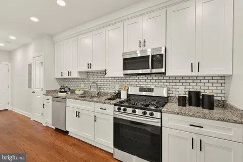 a kitchen with stainless steel appliances white cabinets a stove top oven a sink and dishwasher
