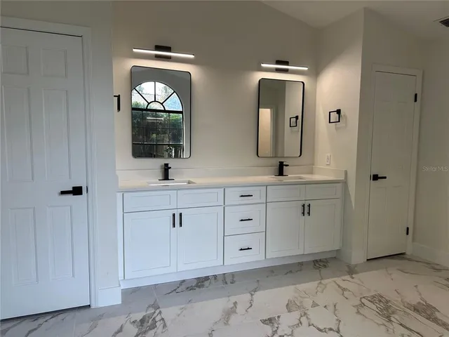 a view of an empty room with window and chandelier fan