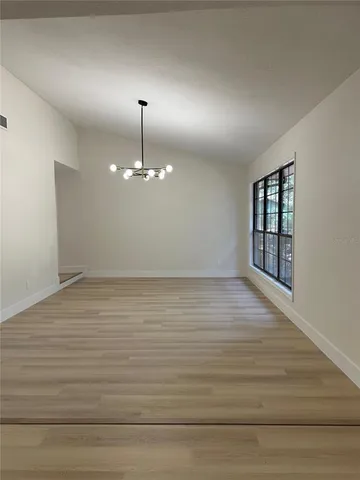 a view of a room with a chandelier fan and wooden floor