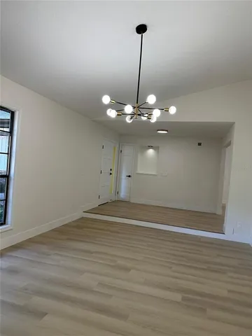 a view of an empty room with window and a kitchen
