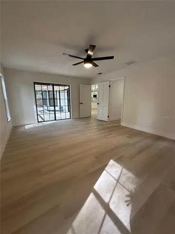 an empty room with windows and fan