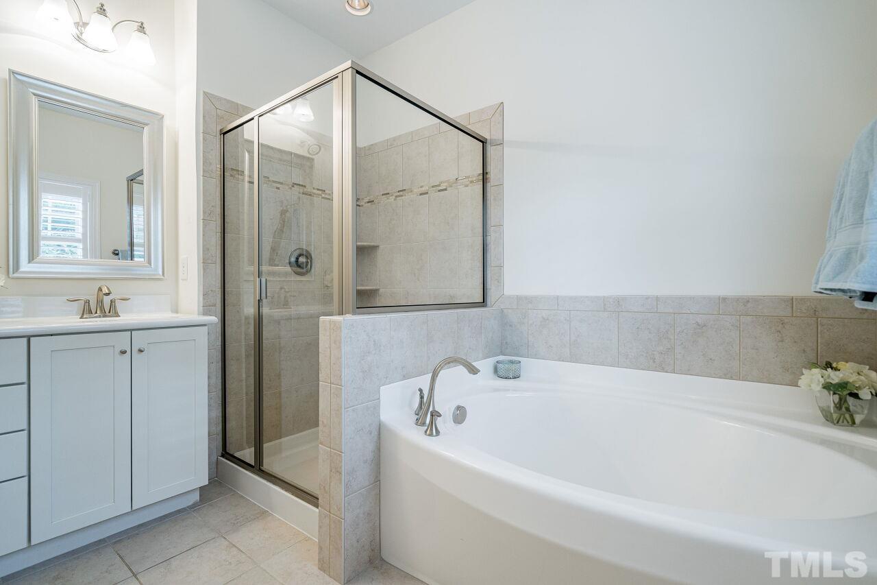 1517 Fullerton Place Raleigh, NC 27607 - Photo 22 of 30 Glamorous owner's suite bathroom with dual sinks, shaker style white cabinets, tile throughout, garden tub & glass enclosed shower.