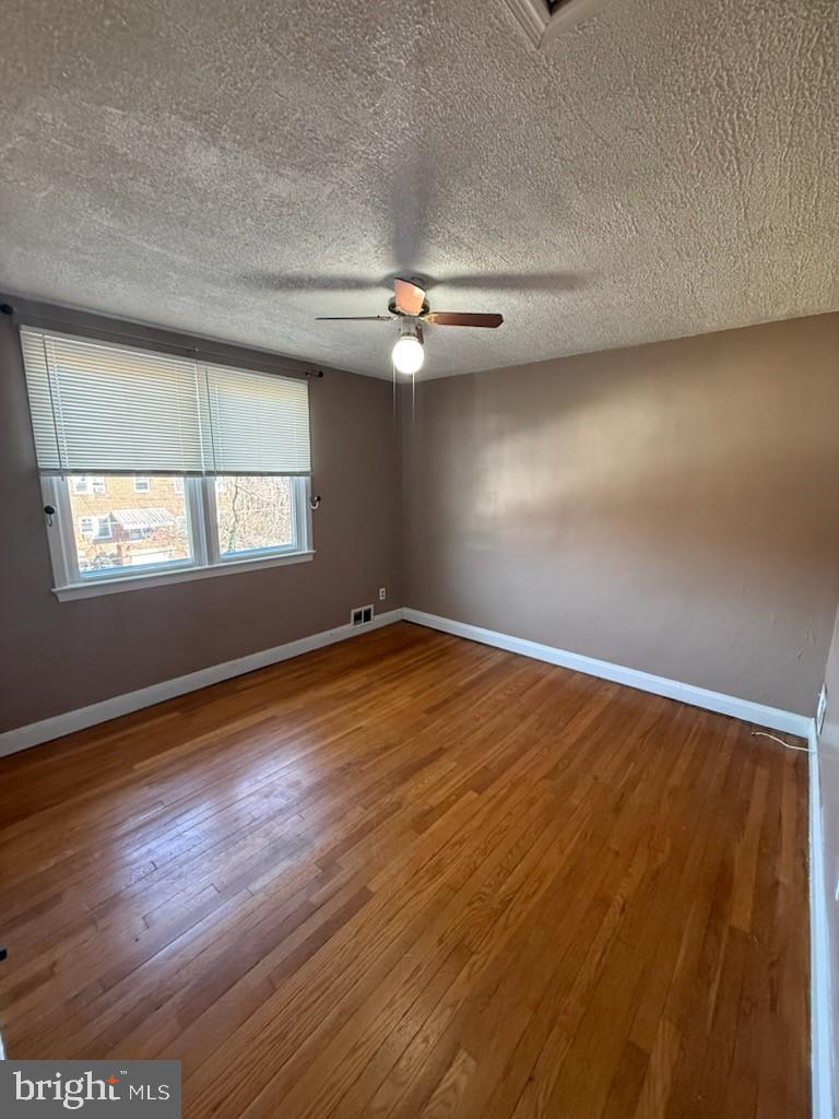 49 Briarwood Road Baltimore, MD 21228 - Photo 5 of 9 an empty room with wooden floor chandelier fan and windows