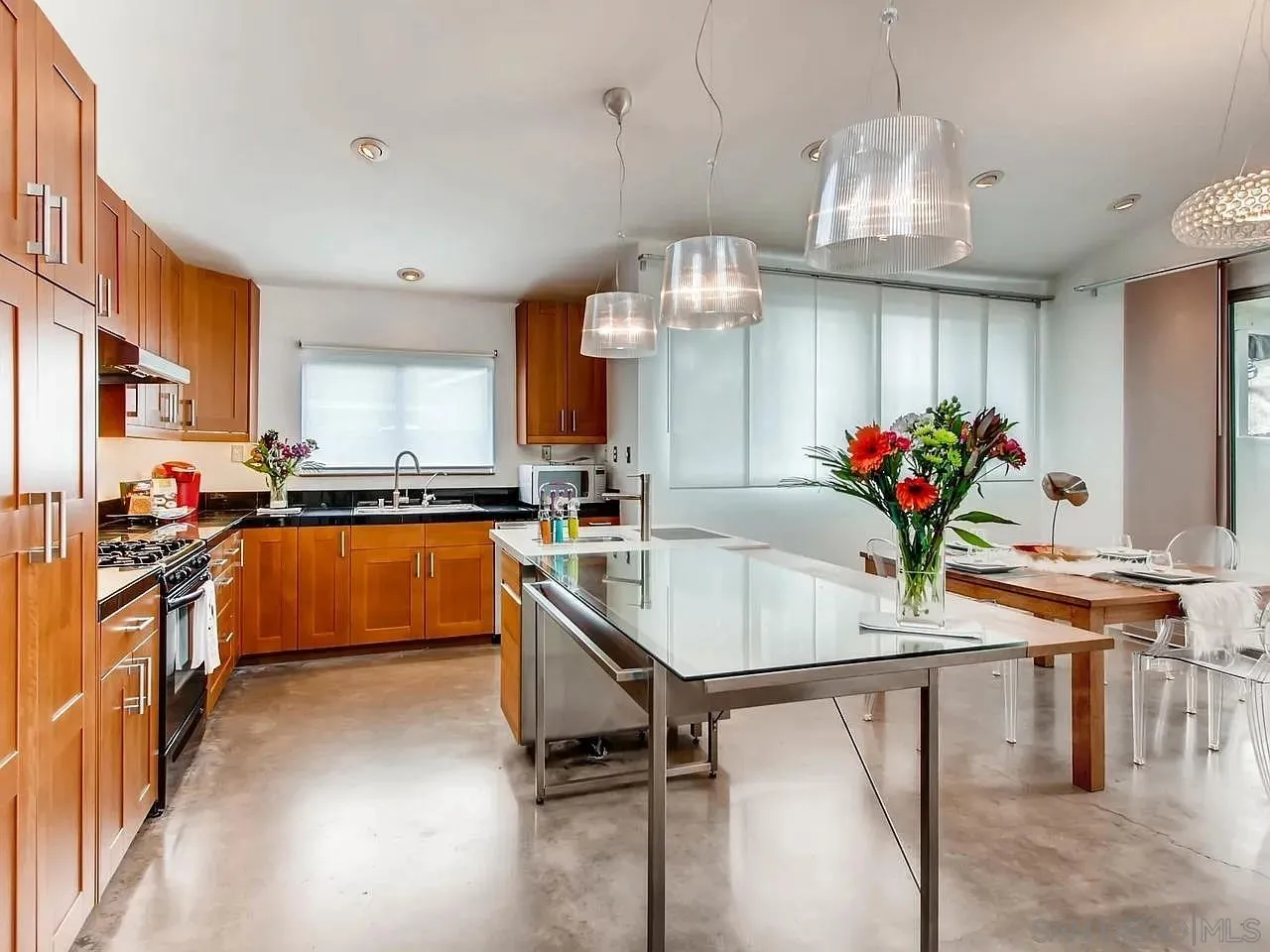 6428 Shirehall Drive San Diego, CA 92111 - Photo 3 of 15 a kitchen with stainless steel appliances kitchen island granite countertop a table chairs in it and wooden floors