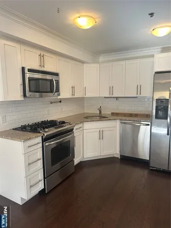 a white kitchen with granite countertop a stove top oven microwave and cabinets