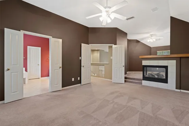 a view of a livingroom with a fireplace a ceiling fan and wooden floor