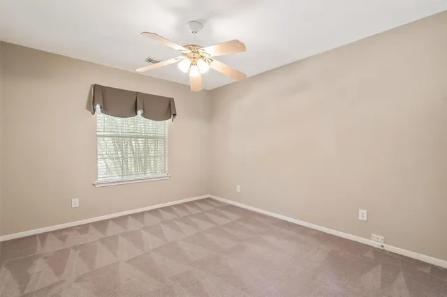 an empty room with chandelier fan and windows