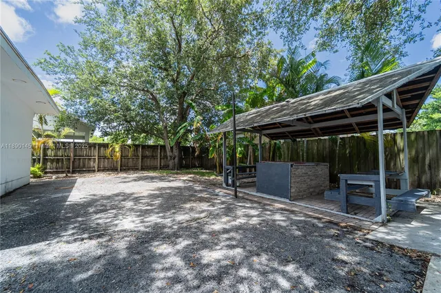 a view of backyard with wooden fence and a large tree