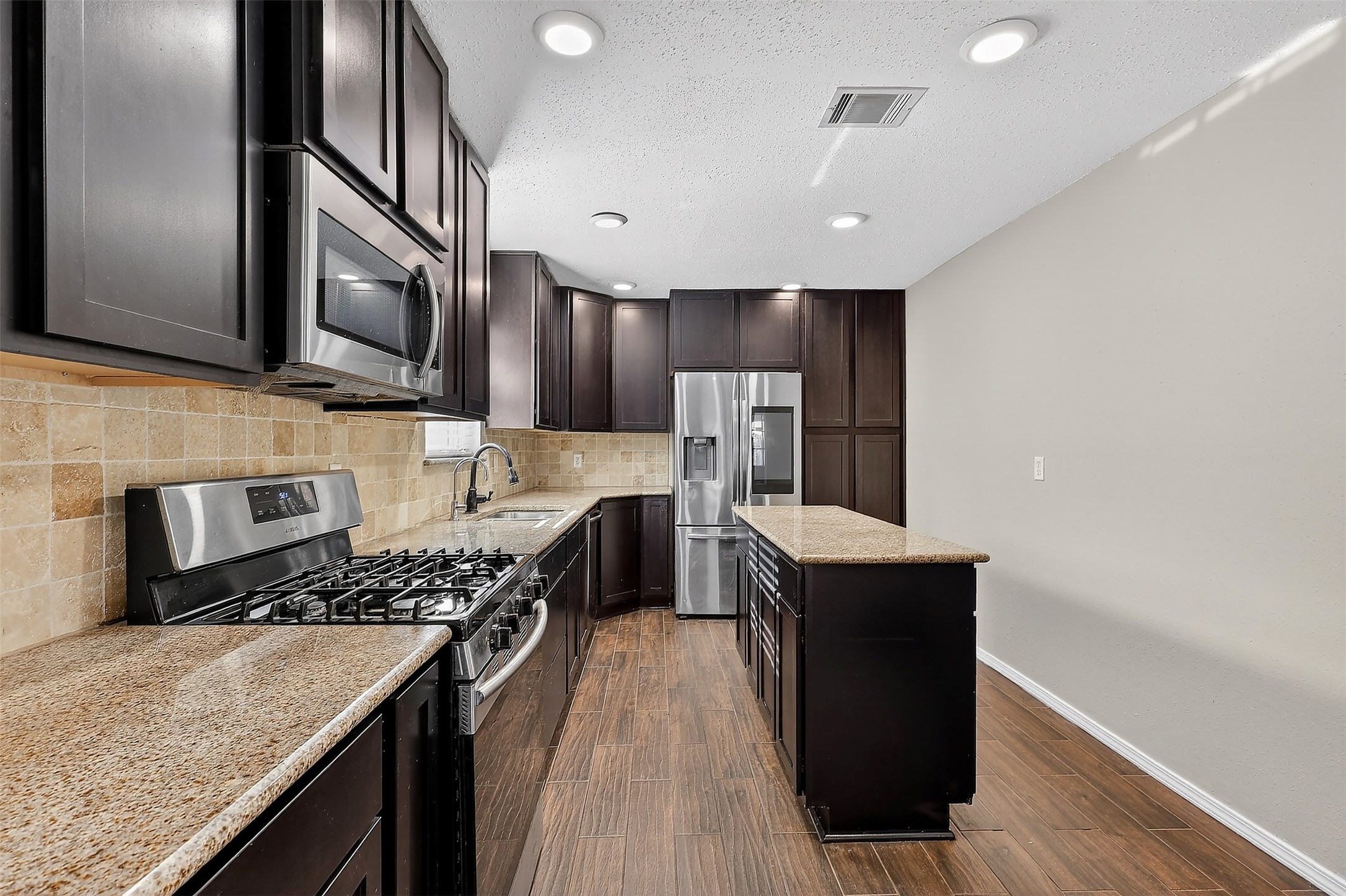 3027 Windmill Street Sugar Land, TX 77479 - Photo 9 of 36 a kitchen with stainless steel appliances granite countertop a stove a sink dishwasher and a refrigerator with wooden floor