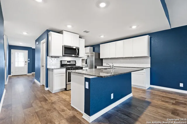 a kitchen with stainless steel appliances granite countertop a stove top oven a sink and a refrigerator