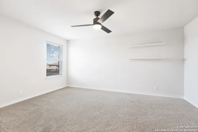 an empty room with windows and ceiling fan