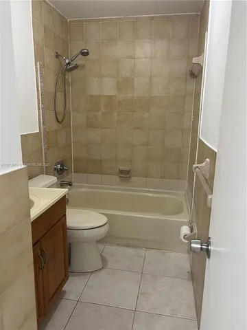 a bathroom with a granite countertop bathtub shower sink vanity and toilet