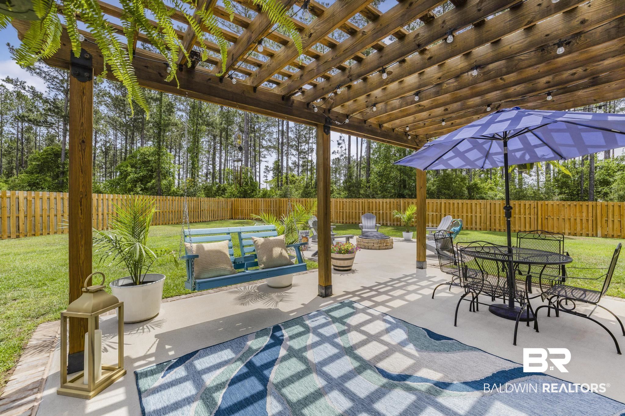 31806 Bobwhite Road Daphne, AL 36527 - Photo 42 of 59 Fenced backyard with a pergola, a patio area, outdoor dining area, and a fire pit
