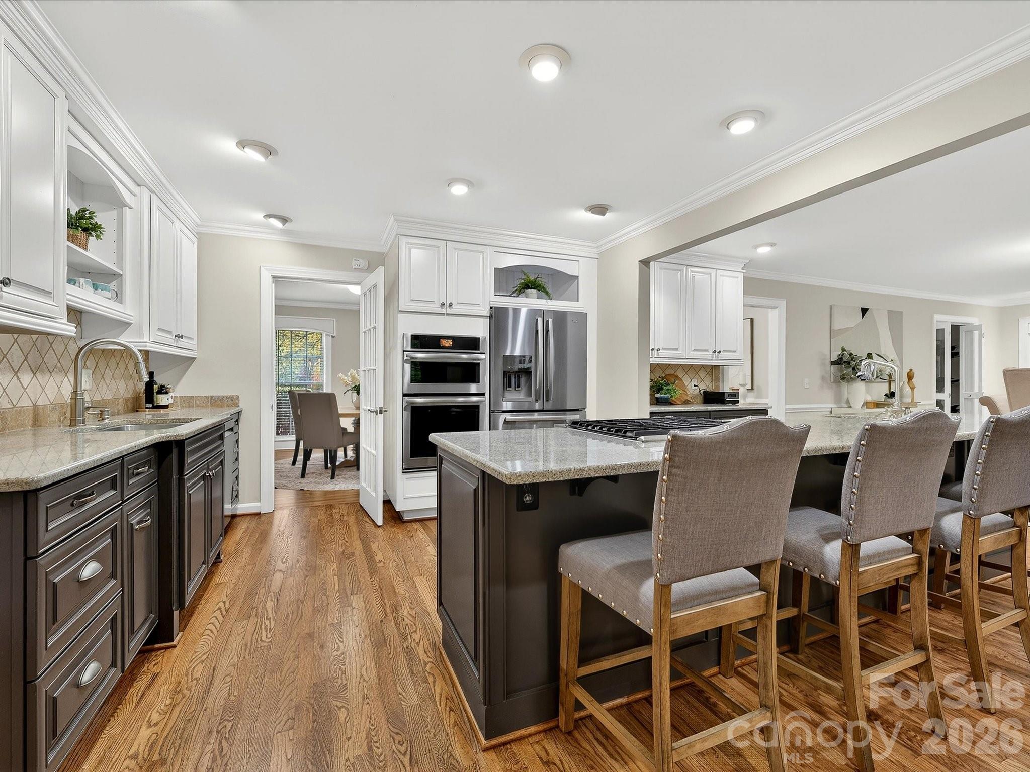 6344 Dovefield Road Charlotte, NC 28277 - Photo 10 of 46 a kitchen with stainless steel appliances granite countertop a stove top oven a sink dishwasher a dining table and chairs with wooden floor