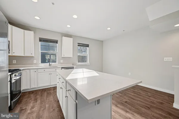 a kitchen with granite countertop a sink and dishwasher a stove top oven with wooden floor