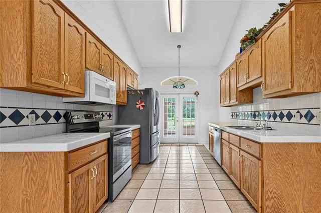 a kitchen with stainless steel appliances granite countertop a stove a sink dishwasher and a refrigerator with wooden floor