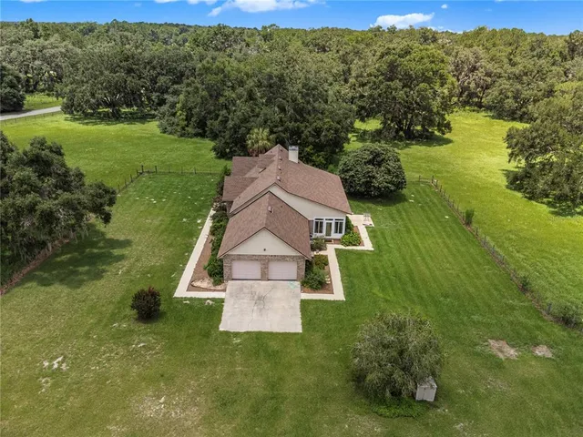 an aerial view of residential house with outdoor space and trees all around