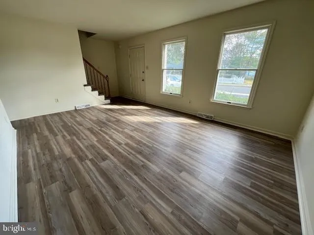 a view of empty room with window and wooden floor