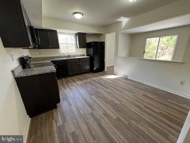 a kitchen with granite countertop wooden floors a stove and black appliances