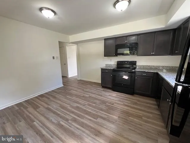 a kitchen with stainless steel appliances a stove top oven a sink a refrigerator white cabinets and wooden floor