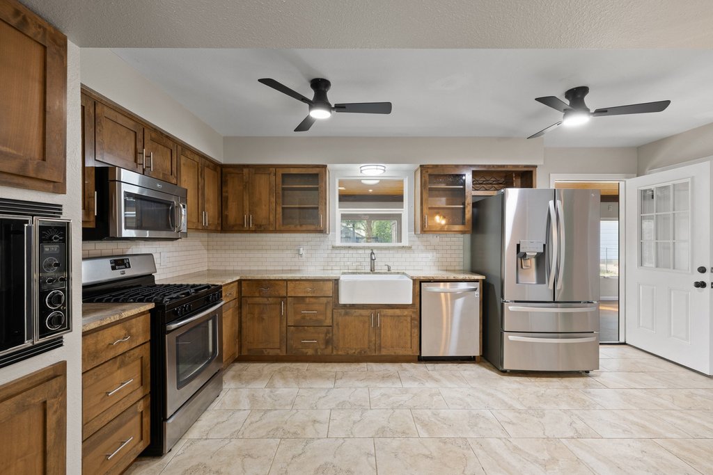 2206 Jacks Pass Austin, TX 78734 - Photo 10 of 35 a kitchen with stainless steel appliances granite countertop a refrigerator a stove a sink a microwave and wooden cabinets